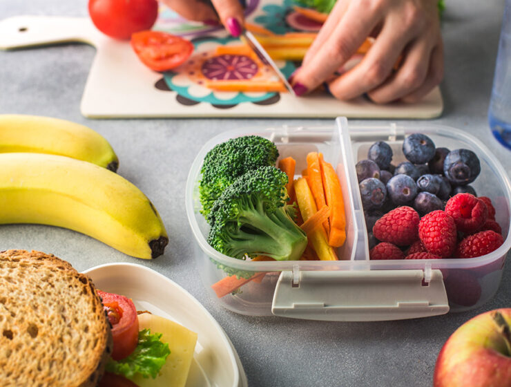 Healthy meal prep with fresh fruits and vegetables, including blueberries, raspberries, broccoli, carrots, bananas, and a sandwich, perfect for a balanced diet.