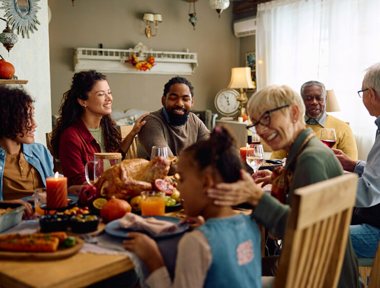 Family gathered around a festive table enjoying a holiday meal with roasted turkey and seasonal decorations.
