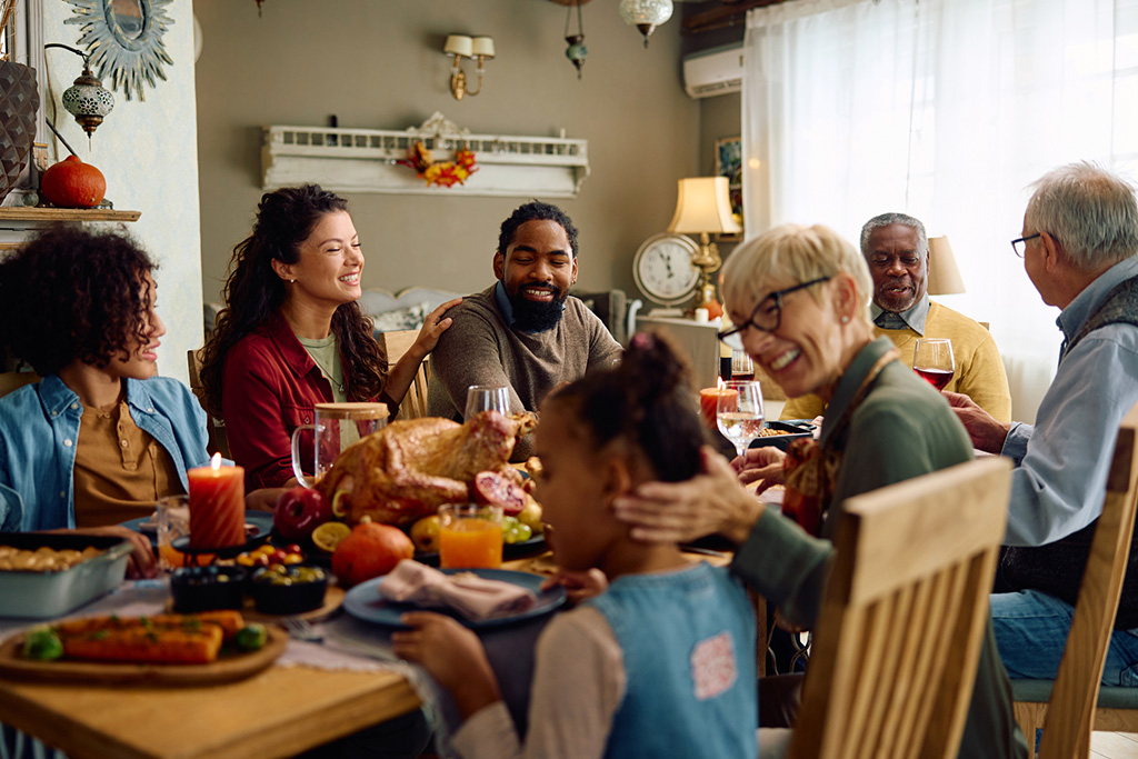 Family gathered around a festive table enjoying a holiday meal with roasted turkey and seasonal decorations.